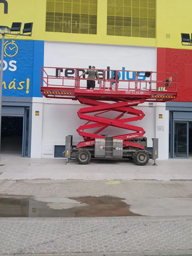 Plataforma de tijera trabajando en fachada comercial